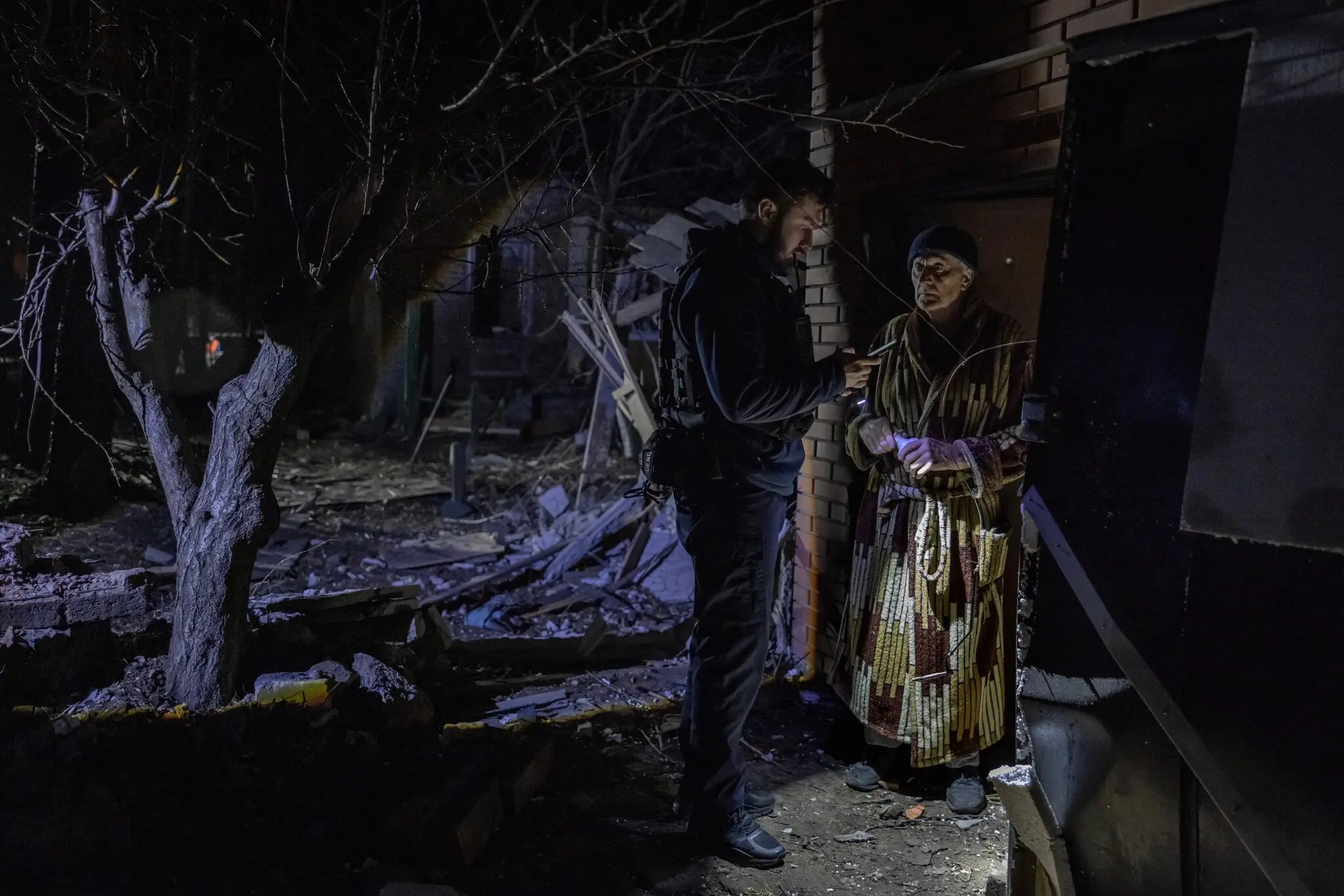 Поліцейський бере інтерв'ю у 71-річного Володимира Садового на місці атаки дрона у березні, внаслідок якої загинув його сусід у Харкові.